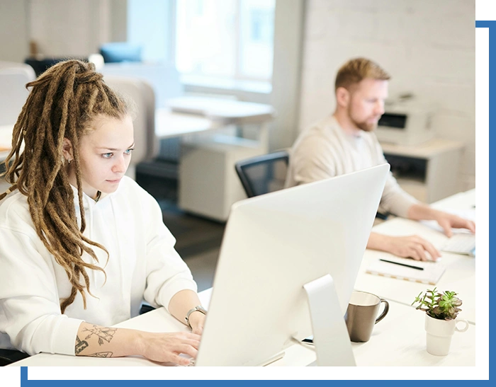 A group of people sitting at tables with computers.