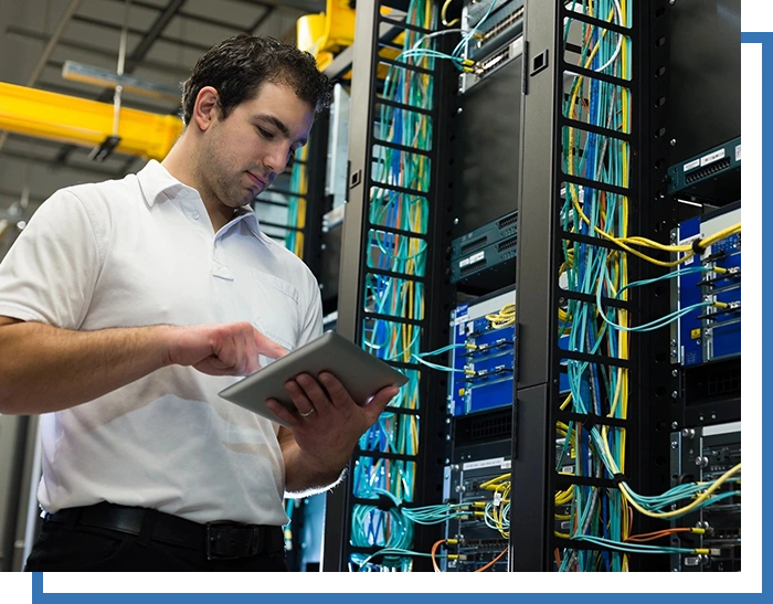 A man holding a tablet in front of server racks.